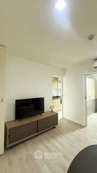 Modern living room with sleek TV stand and open view to kitchen area.