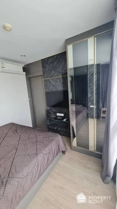 Modern bedroom with sleek design and mirrored wardrobe in a stylish apartment.