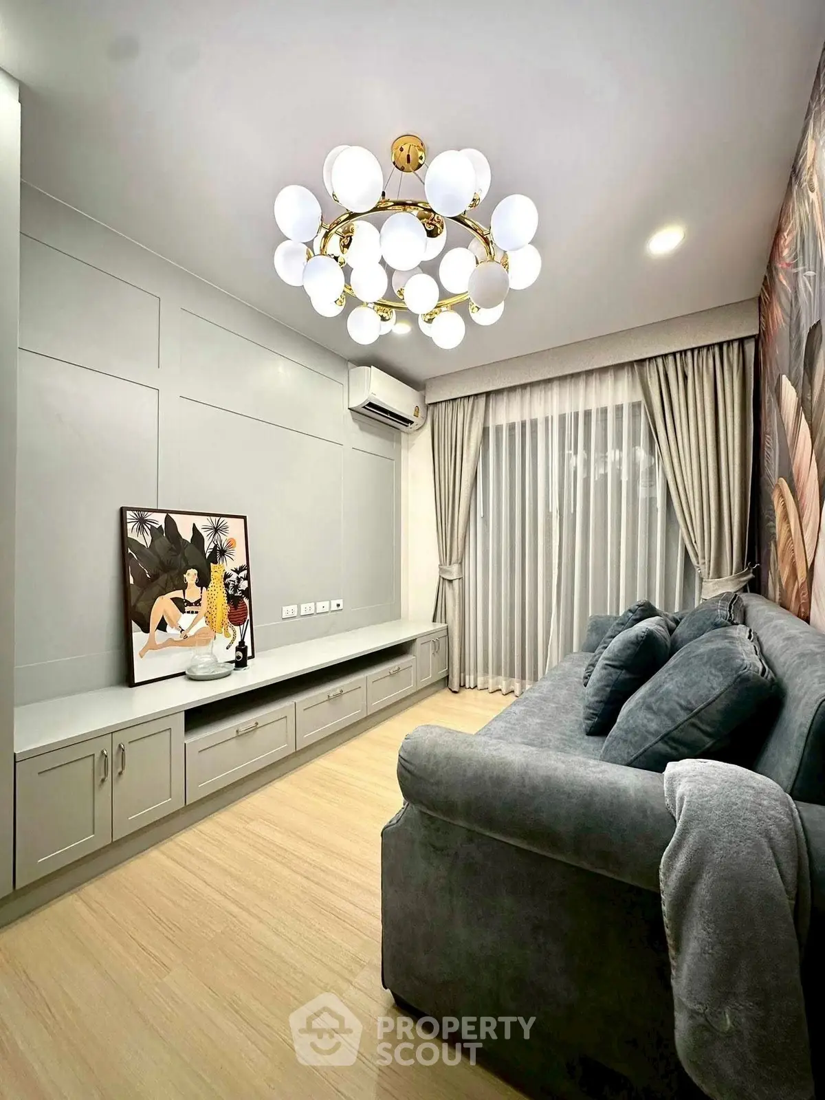 Elegant living room with modern chandelier and cozy sofa, featuring stylish wall art and floor-to-ceiling curtains.