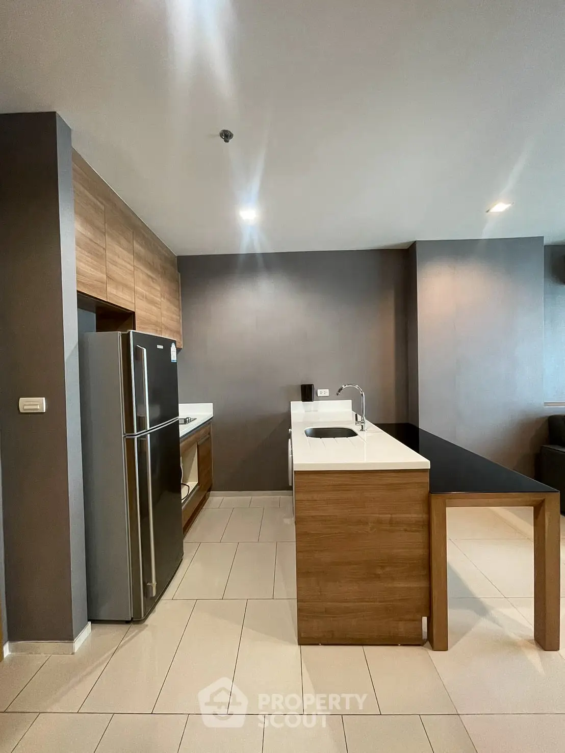 Modern kitchen with sleek design, featuring stainless steel fridge and wooden cabinetry.