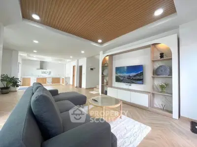 Spacious modern living room with stylish decor and open layout, featuring a cozy sofa and elegant wooden ceiling.