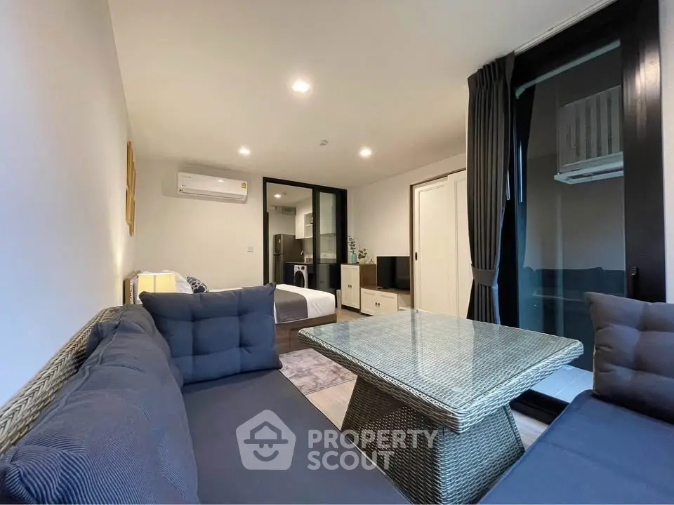 Modern living room with cozy seating and open view to bedroom