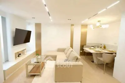 Modern living room with elegant decor and open dining area, featuring a sleek TV setup and stylish lighting.