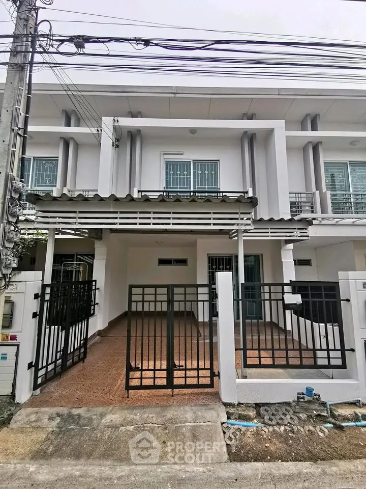 Modern townhouse exterior with gated entrance and tiled driveway in a suburban neighborhood.