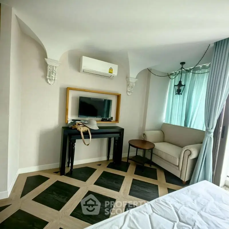 Charming bedroom with elegant decor and natural light, featuring a cozy seating area and stylish flooring.