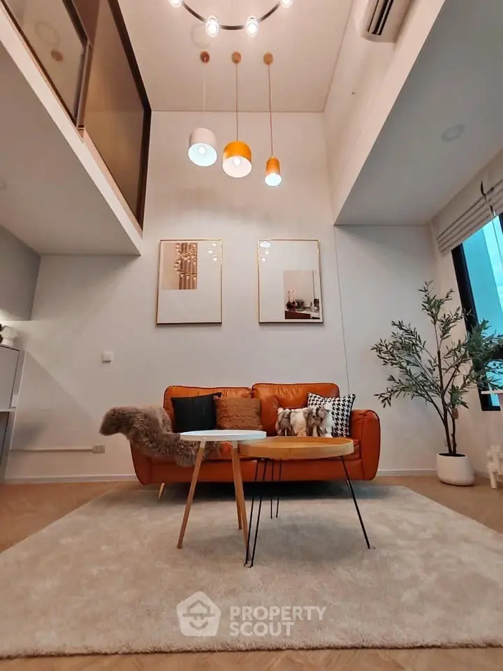 Modern living room with high ceiling, stylish lighting, and cozy seating area.