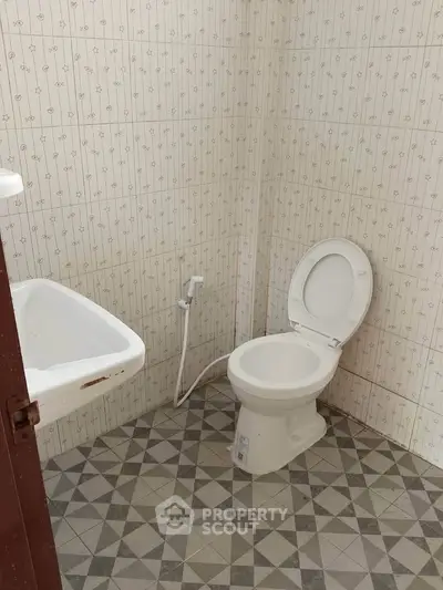 Compact bathroom with tiled walls and floor, featuring a toilet and sink.