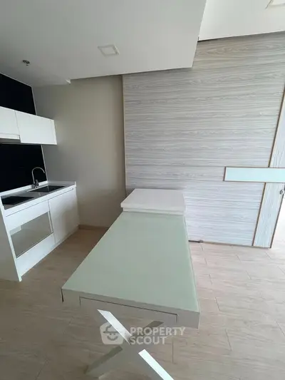 Modern kitchen with sleek design and glass-top table in a contemporary apartment.