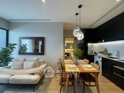 Chic modern apartment with an open layout connecting a cozy living area to a sleek kitchen, accentuated by stylish lighting and decor.