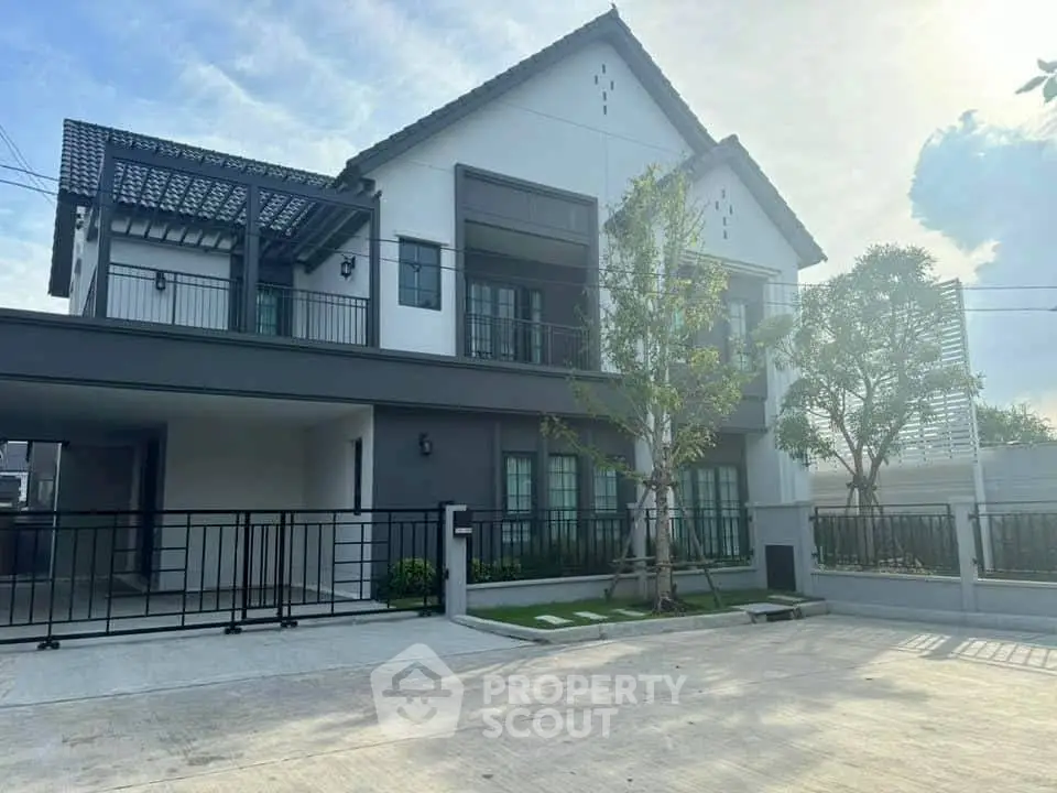 Modern two-story house with spacious driveway and contemporary design, featuring large windows and a sleek facade.