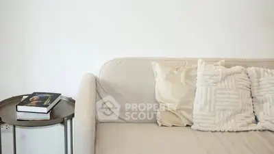 Cozy living room with beige sofa and decorative pillows, perfect for relaxation.