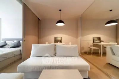 Modern living room with cozy white sofa and elegant dining area in open layout apartment.