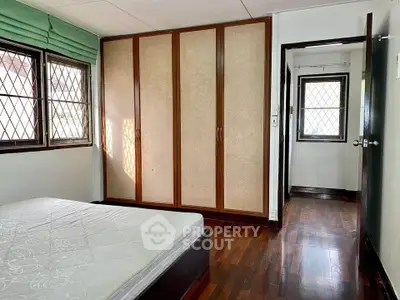 Spacious bedroom with large windows and built-in wardrobe, featuring hardwood floors and natural light.