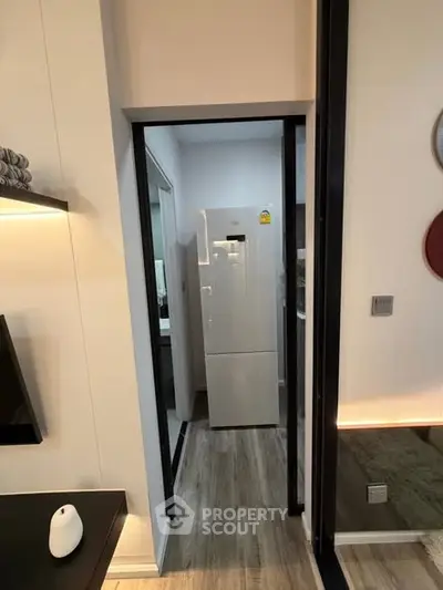 Modern apartment interior with sleek design and stylish decor, featuring a compact kitchen area with a refrigerator.