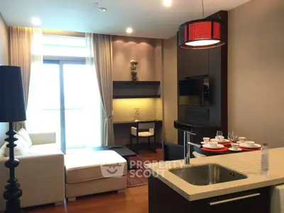 Modern living room with open kitchen, stylish decor, and natural light from large window.