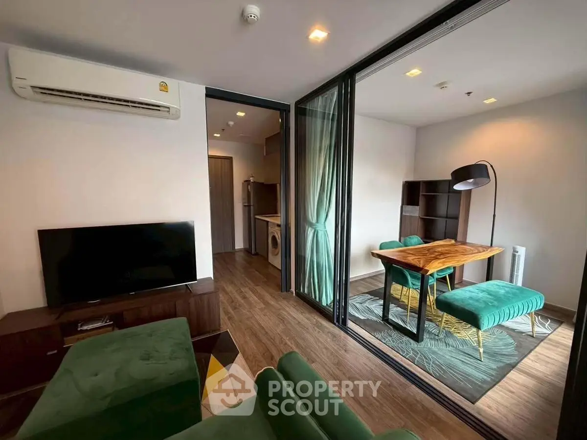 Modern living room with green sofa, TV, and dining area in stylish apartment