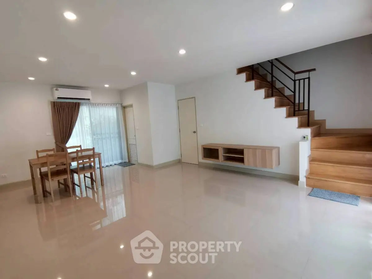 Spacious modern living room with dining area and wooden staircase