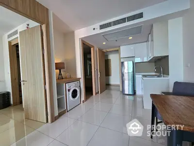 Spacious modern apartment with a sleek open kitchen layout, featuring built-in appliances, ample storage, and a convenient laundry area.