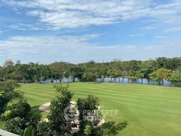 Stunning view of lush green golf course with serene water backdrop