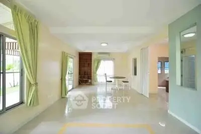 Spacious open-plan living area with large windows and green curtains