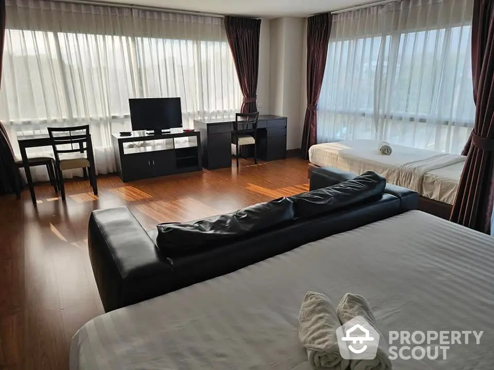 Spacious bedroom with large windows and modern furnishings, perfect for comfort and relaxation.