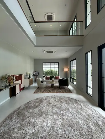 Spacious modern living room with high ceilings and large windows, featuring elegant decor and cozy seating area.