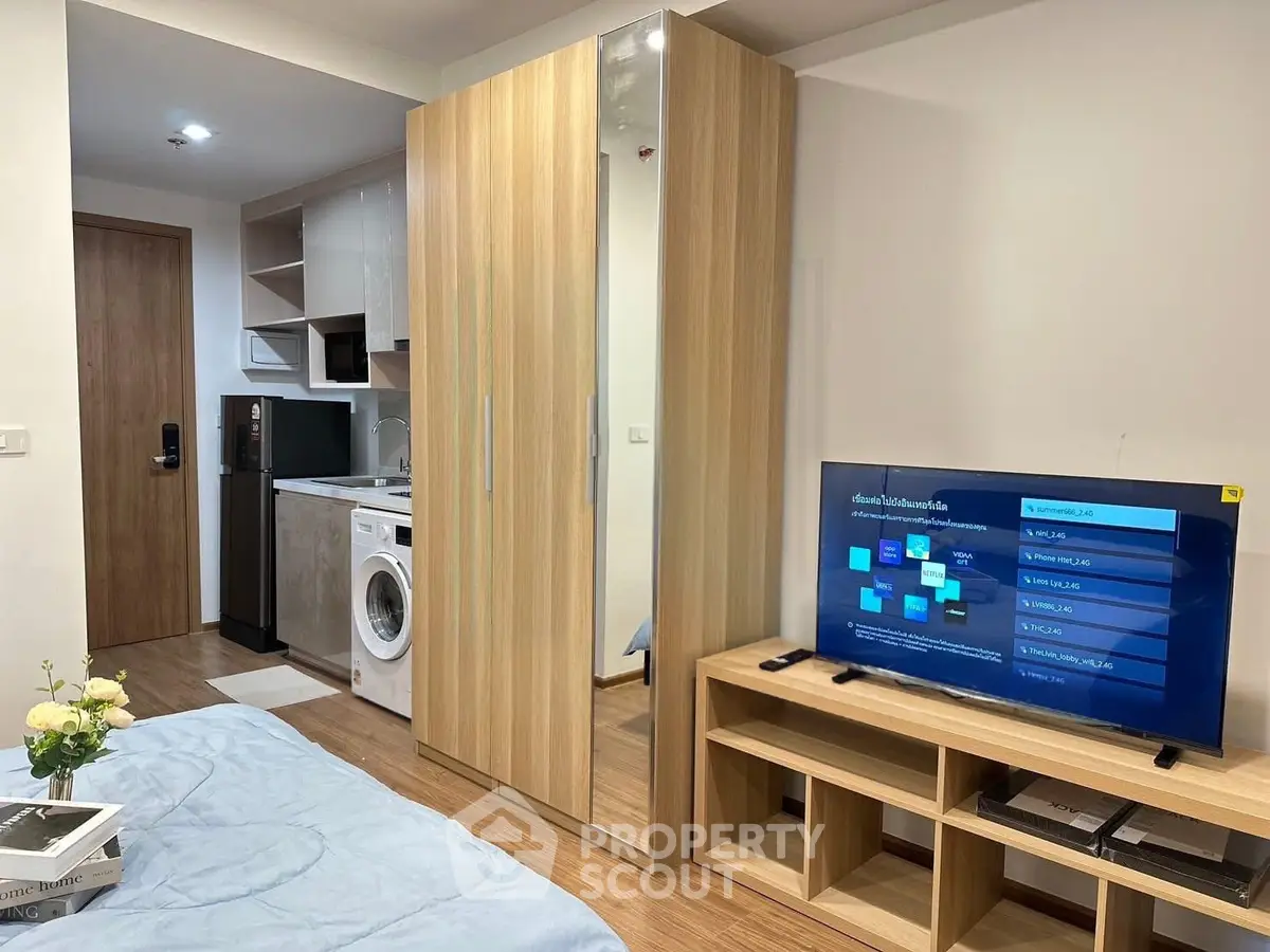 Modern studio apartment with wooden flooring, built-in wardrobe, washing machine, and flat-screen TV.