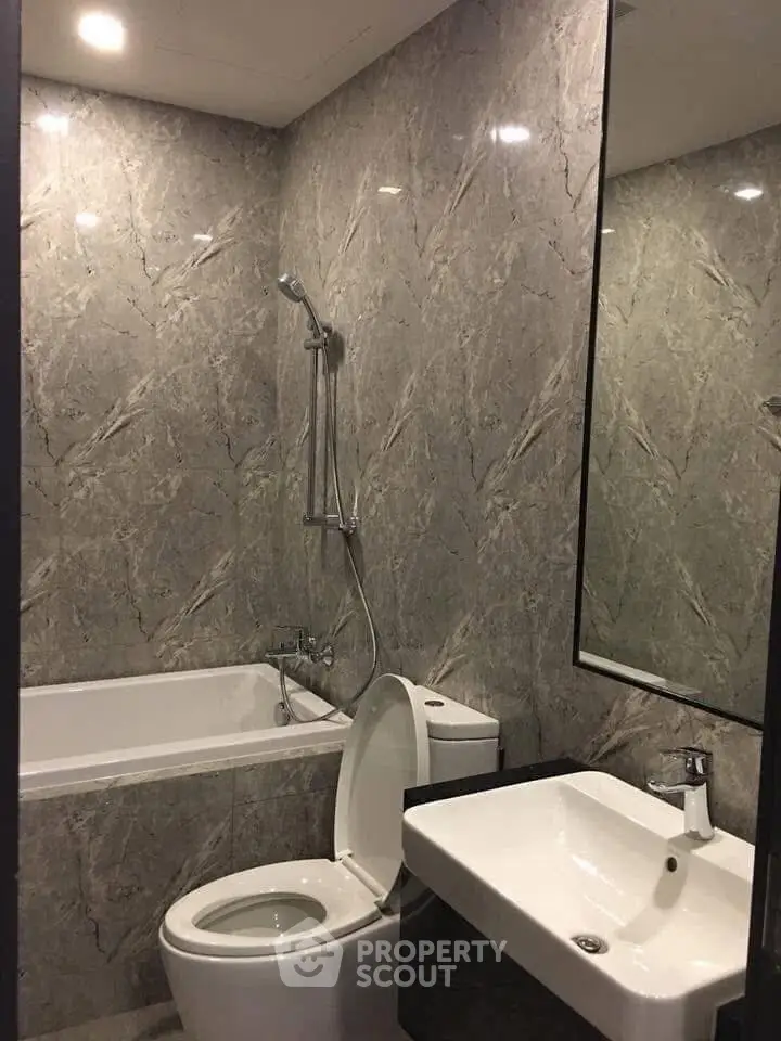 Modern bathroom with marble walls, bathtub, and sleek fixtures.