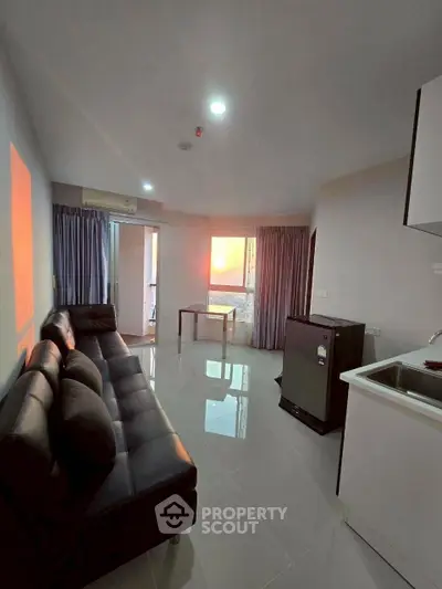 Modern living room with sleek black sofa and sunset view through large windows.