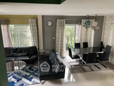 Modern living and dining area with sleek black furniture and large windows.