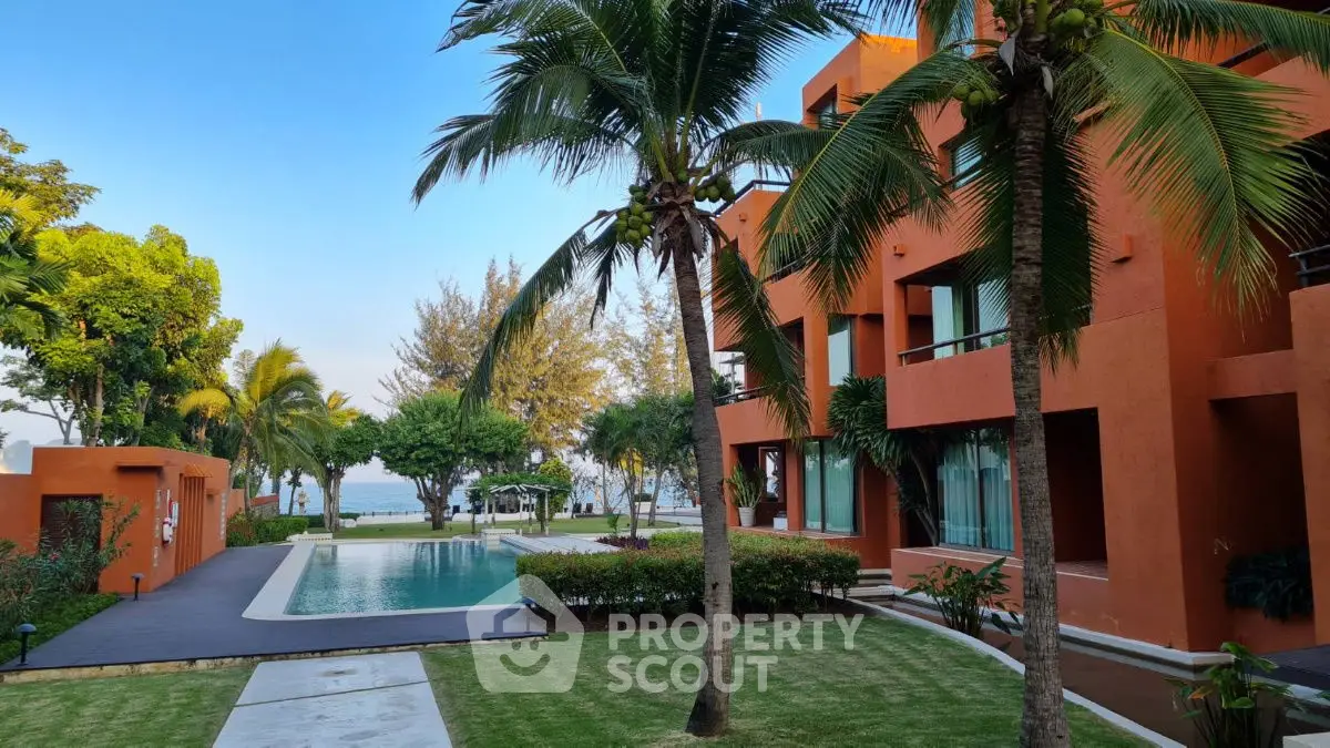 Stunning beachfront property with pool and lush palm trees, perfect for luxury living.