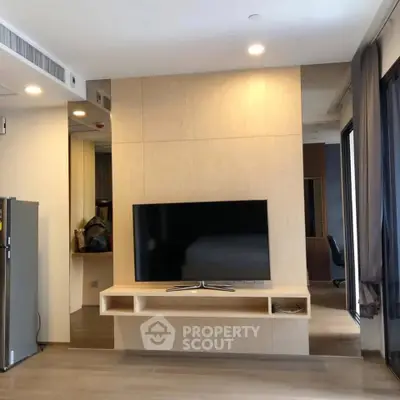 Modern living room with sleek TV setup and open layout, featuring stylish wooden paneling and large windows.