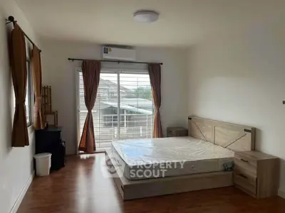 Spacious bedroom with natural light, featuring a large window and modern furnishings.