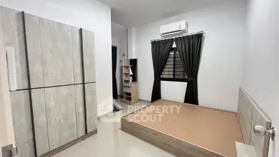 Spacious and modern bedroom with large bed platform, sleek built-in wardrobe, and air conditioning unit, perfect for urban living.