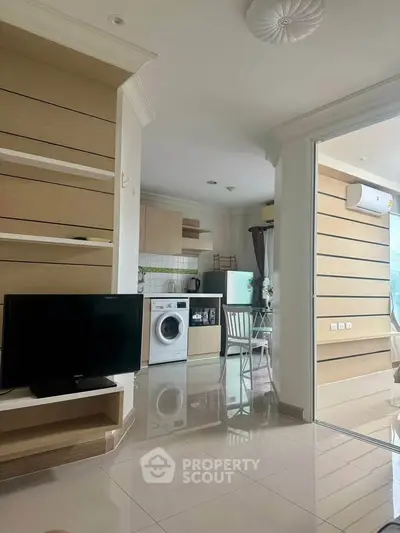Modern open-layout living room with kitchen, featuring sleek furniture and appliances, ideal for urban living.