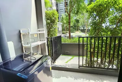 Charming balcony with lush garden view and modern washing machine, perfect for urban living.