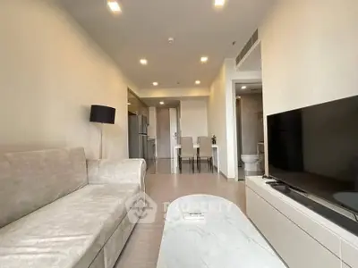 Modern living room with sleek furniture and open layout, featuring a cozy sofa and large TV.