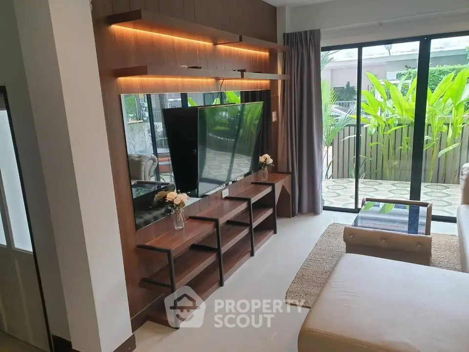Modern living room with stylish TV unit and large sliding glass doors opening to lush garden view.