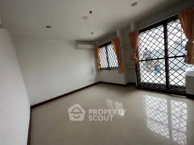 Spacious unfurnished room with large windows and security bars, ideal for customization.