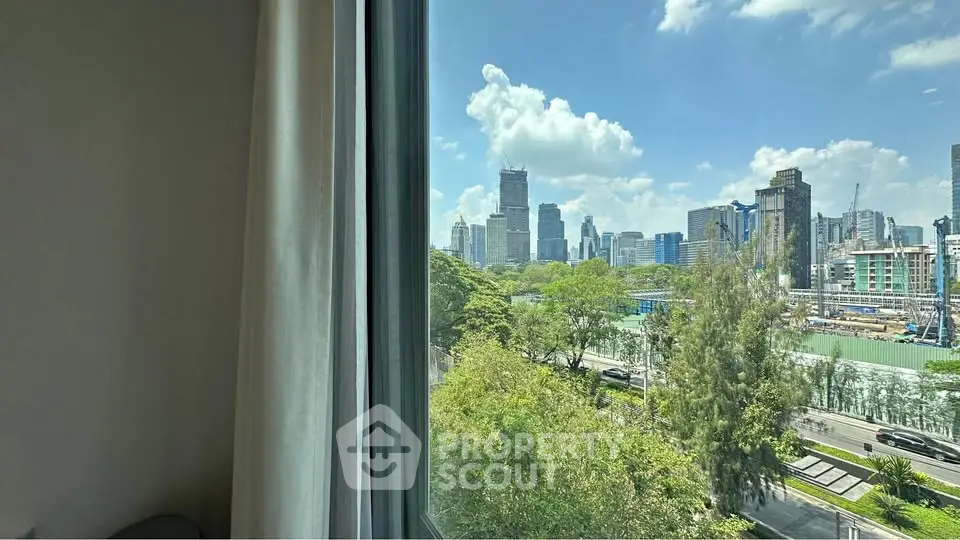 Stunning cityscape view from a high-rise apartment window with lush greenery and blue skies.