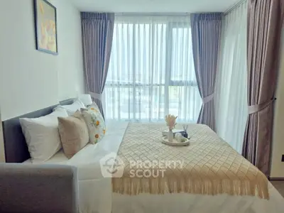 Cozy bedroom with elegant decor and large windows offering natural light.