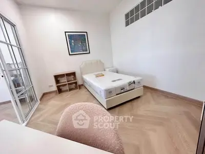 Spacious bedroom with modern decor and natural light, featuring a comfortable bed and stylish flooring.