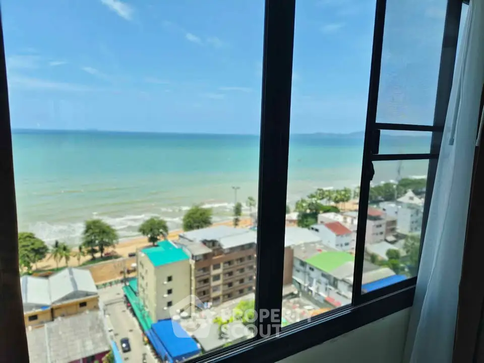 Stunning ocean view from high-rise apartment window overlooking beachfront and cityscape.