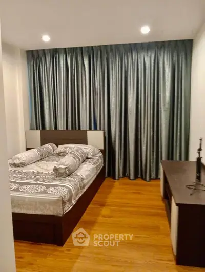 Cozy bedroom with elegant curtains and wooden flooring, perfect for relaxation.