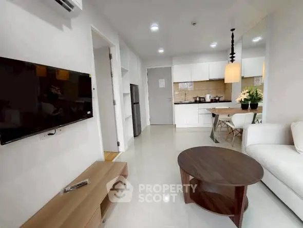 Modern open-layout living room and kitchen with sleek furniture and neutral tones.
