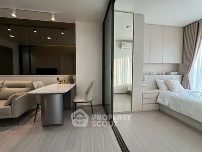 Modern studio apartment with stylish living area and cozy bedroom separated by glass partition.