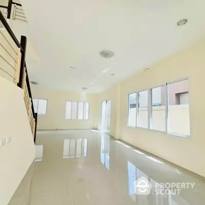 Spacious sunlit living room with glossy tiled floors and large windows