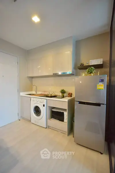 Modern kitchen with washing machine, oven, and fridge in compact layout