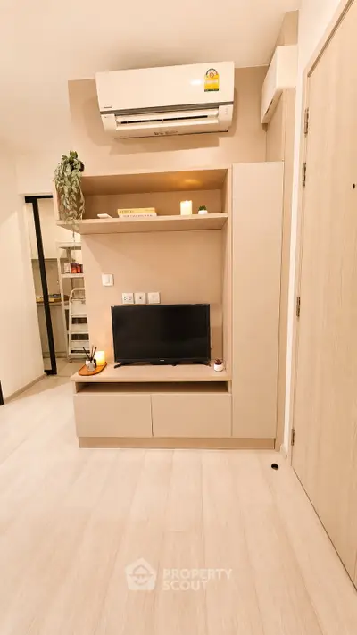 Modern living room with sleek TV unit and air conditioning, showcasing minimalist design and cozy ambiance.