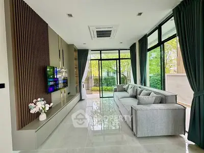 Spacious modern living room with large windows and garden view, featuring sleek decor and comfortable seating.